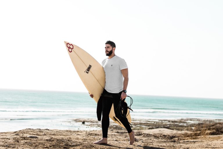 Surfeur marchant avec sa planche sur la plage