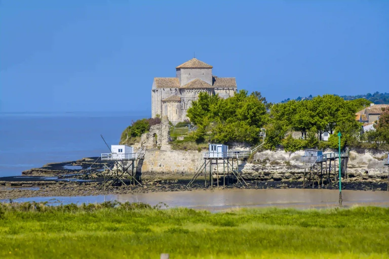 Camping à Talmont-sur-Gironde en Charente-Maritime, vue sur le paysage avec les carrelets et l’église romane au bord de l’estuaire.