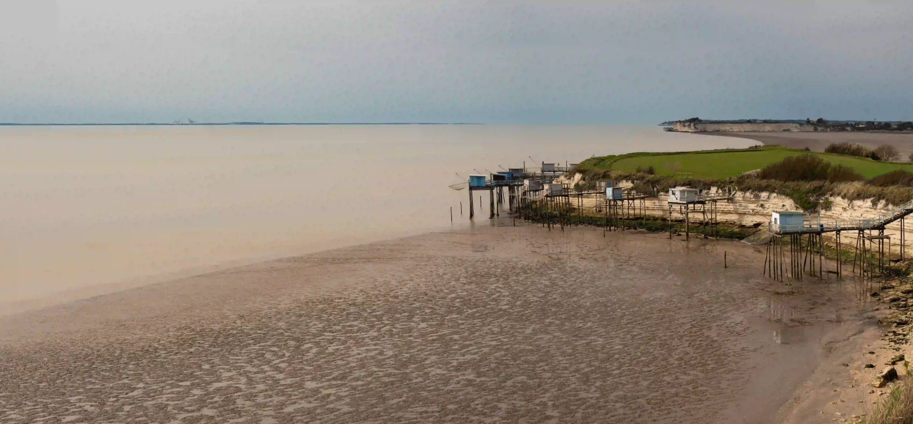 Camping à Meschers-sur-Gironde, plage et carrelets en bord de côte au coucher du jour.