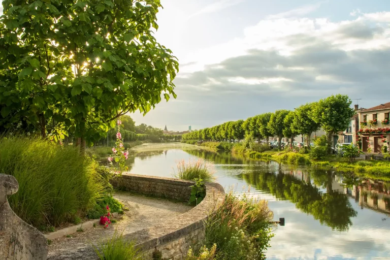 Camping à Saujon en Charente-Maritime, vue sur le village et son canal bordé d’arbres.